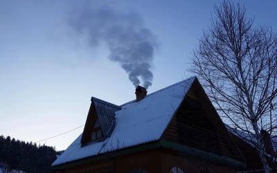 House in winter with snow on the roof and smoke coming from its chimney